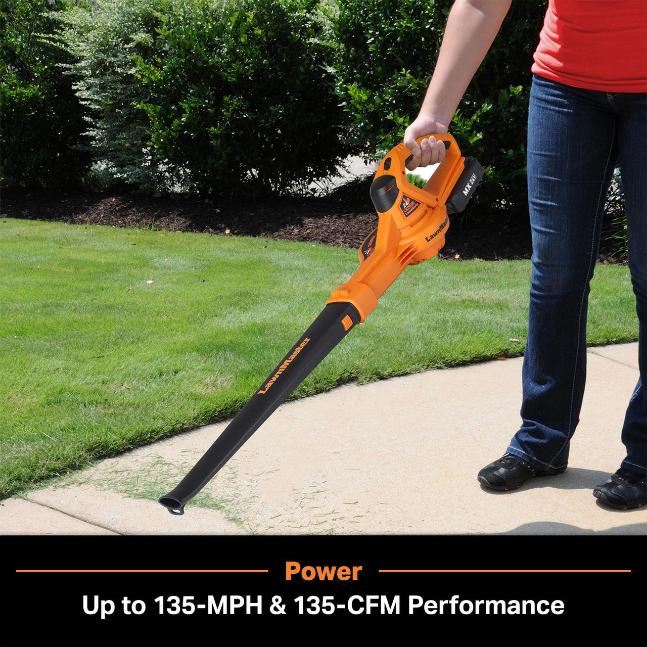 Person using an orange leaf blower on a sidewalk with grass and trees in the background