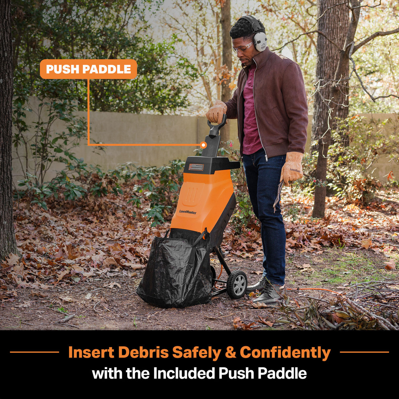 Person using a wood chipper with a push paddle in a wooded area