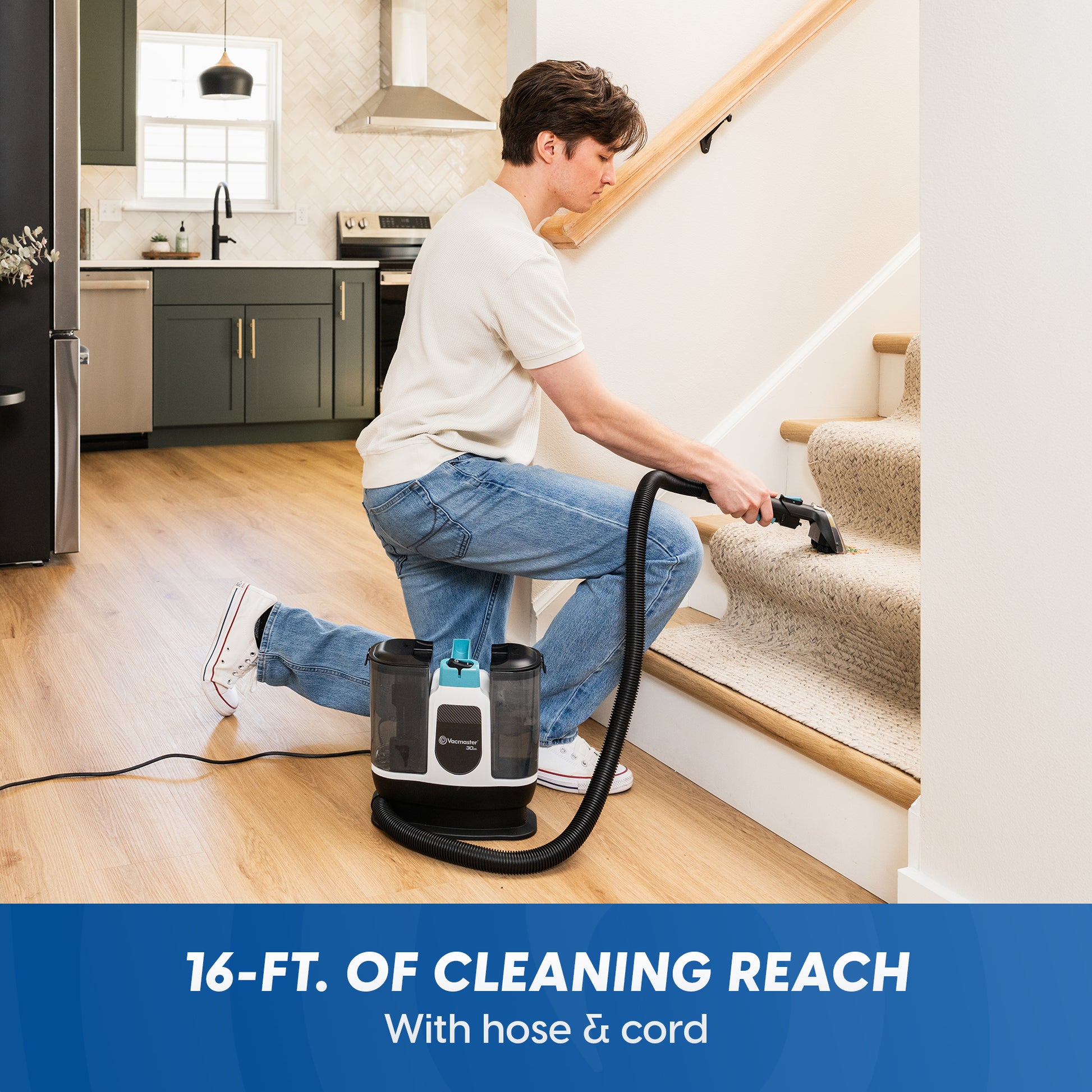 A man kneels on a wooden floor while using a cordless carpet cleaner with a hose and cord to clean carpeted stairs in a home. A blue banner at the bottom reads '16-FT.