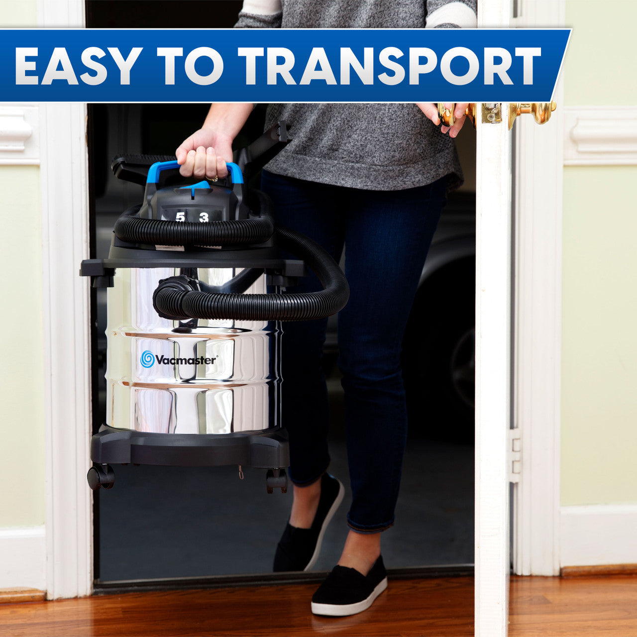 Image of a woman from the upper arms down walking through a doorway holding a shiny stainless steel wet/dry vacuum with text that reads, "easy to transport."