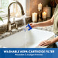 A person at a kitchen sink holds a blue and white washable HEPA cartridge filter under running water from a chrome faucet. The scene includes a granite countertop, lit candles, and a sink, with text at the bottom reading 'WASHABLE HEPA CARTRIDGE FILTER Reusable & budget friendly'.