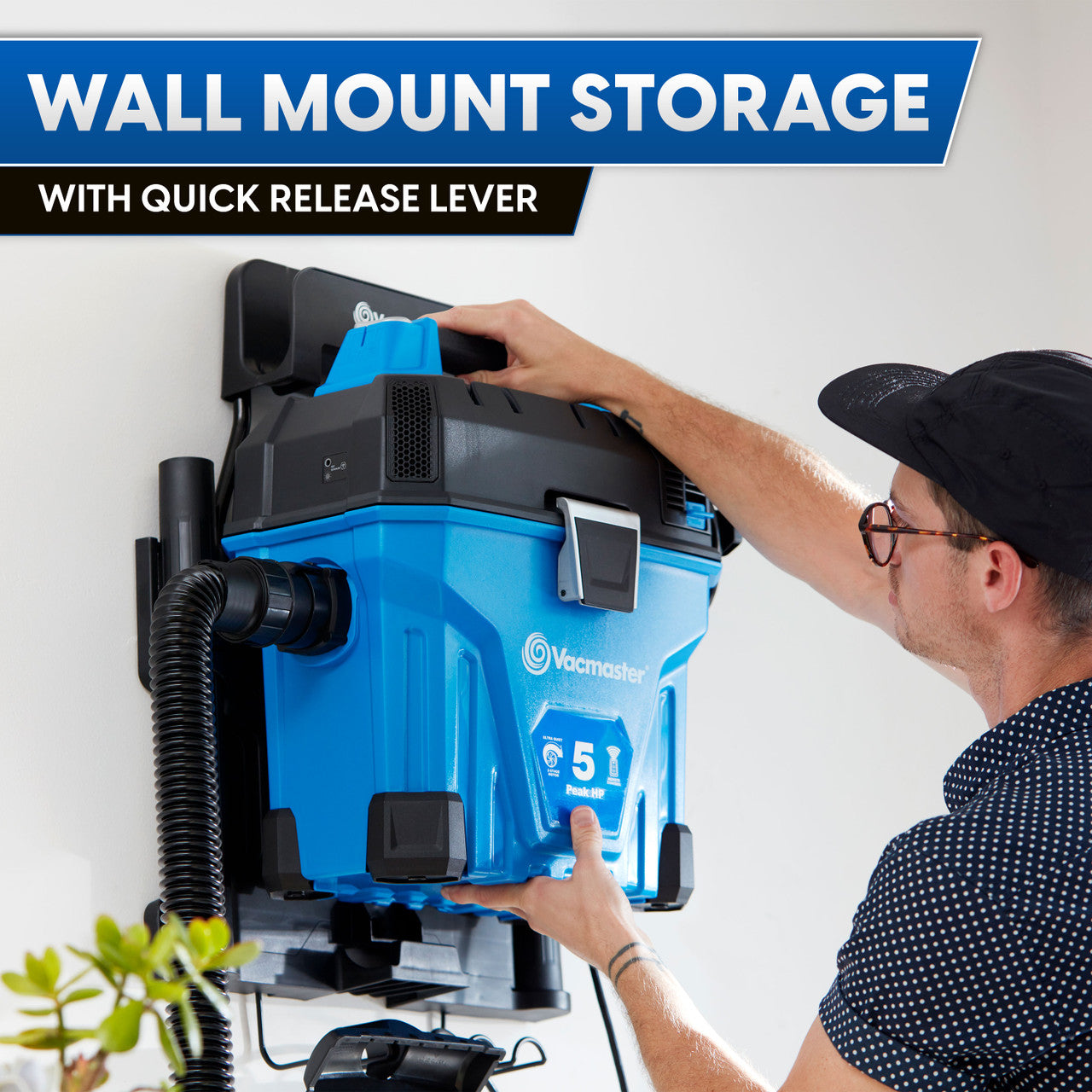 Person using a blue vacuum cleaner with wall mount storage and quick release lever.