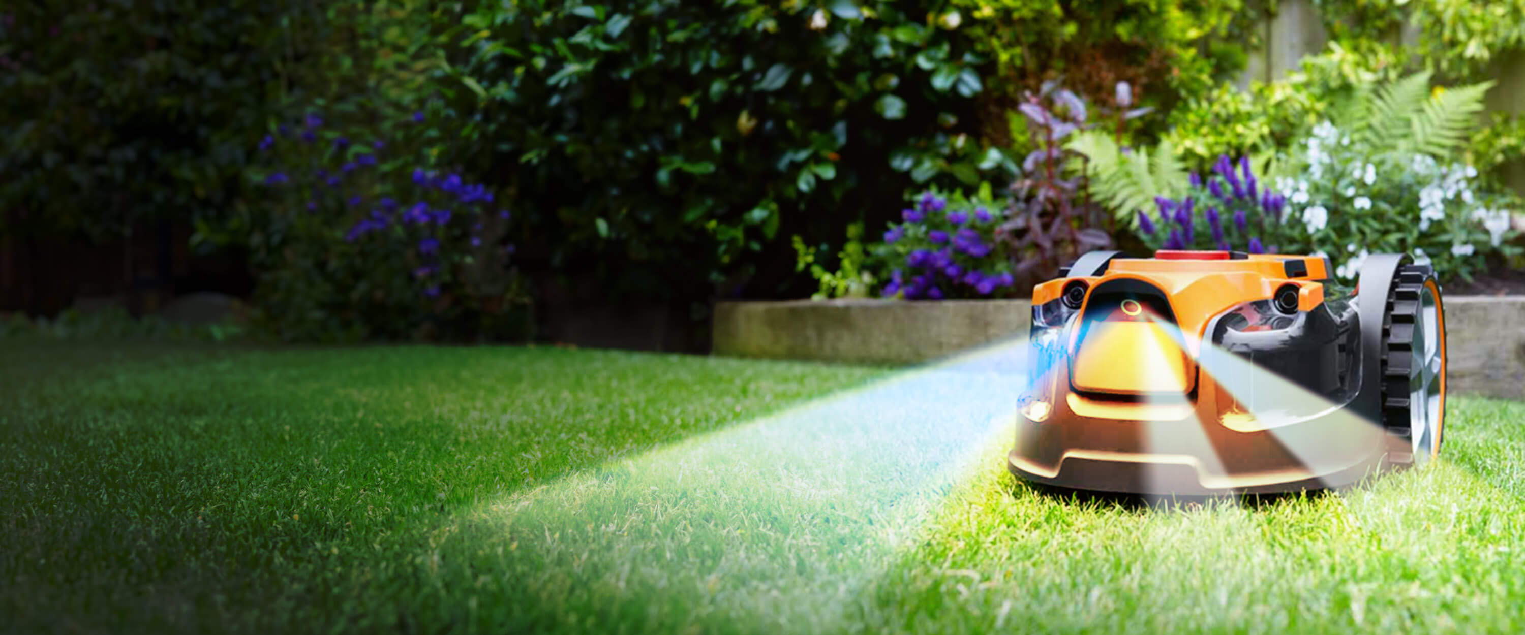Robotic lawn mower cutting grass in a garden with plants and flowers in the background